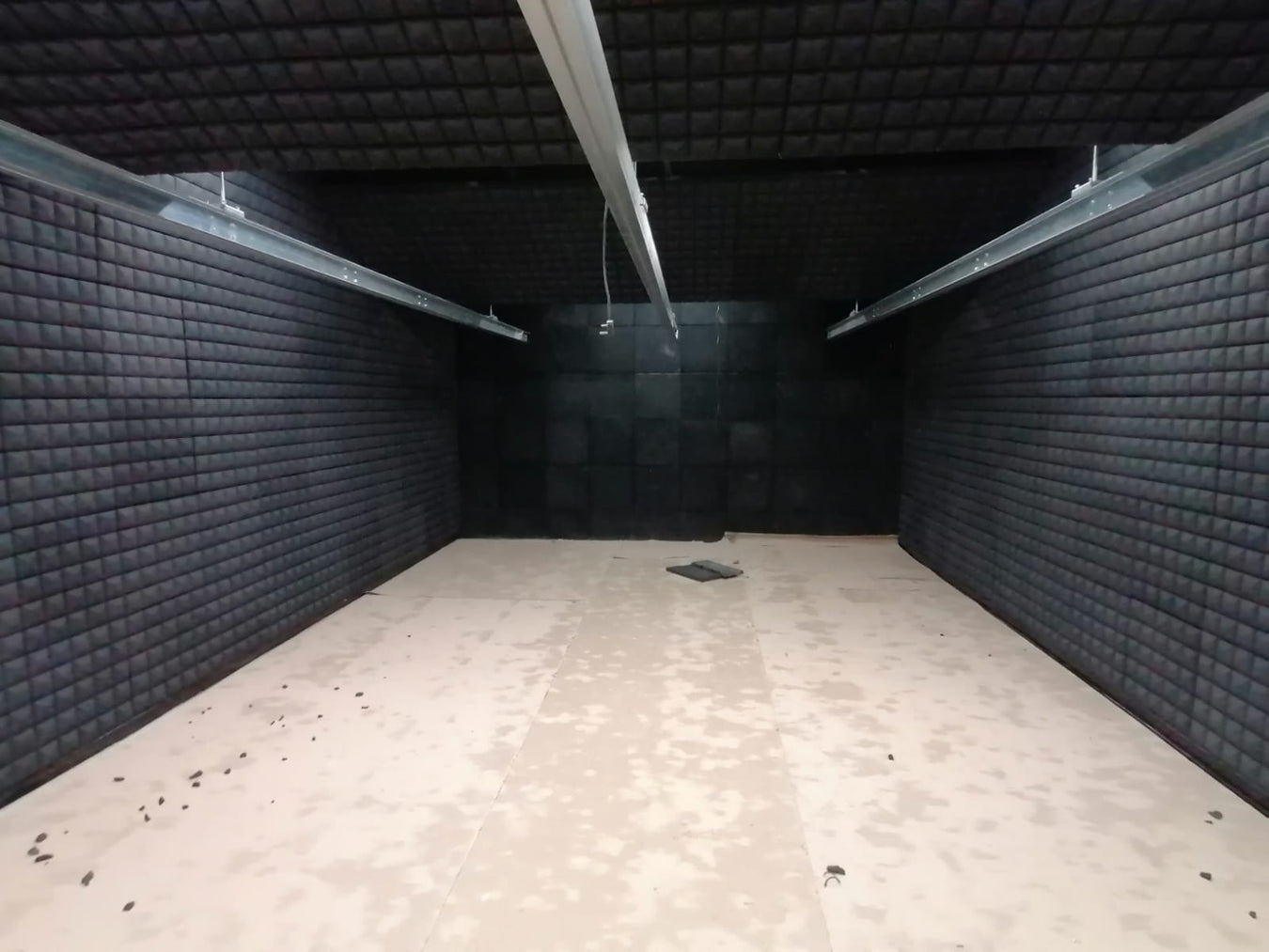 Empty dark room with padded walls and fluorescent lights.